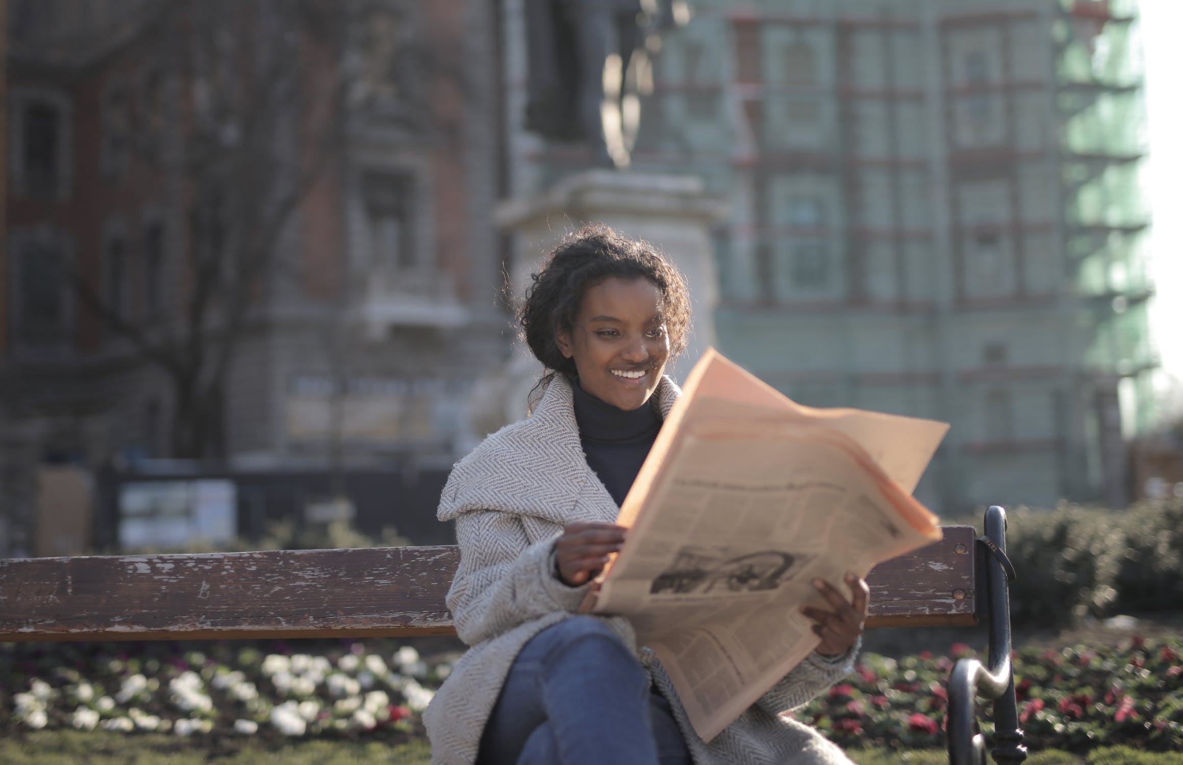 Frau mit Zeitung auf einer Parkbank